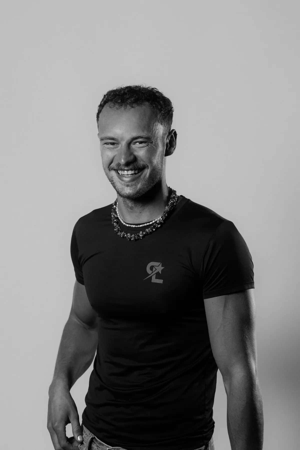 Luke Satterly (Coach Luki) smiling in a Coach Luki training shirt — certified personal trainer and nutritionist in Berlin